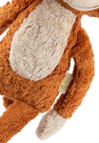 Soft plush monkey toy with orange fur, beige belly and hands, lying diagonally with brand tag visible on side.