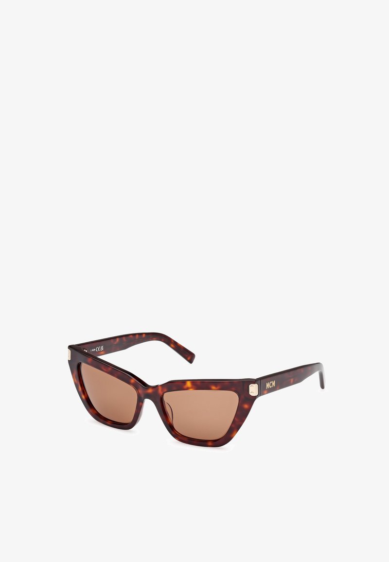 Ochelari de soare în stil tortoise cu rame unghiulare de tip cat-eye, lentile nuanțate de brun și un accent auriu pe braț, având branding-ul MCM.