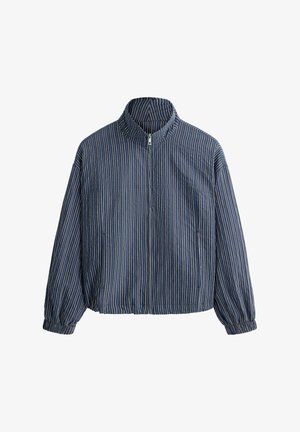 Sininen vetoketjullinen takki, jossa on valkoiset pystysuorat raidat, pitkät hihat, joustavat hihansuut ja pystypystykaulus.