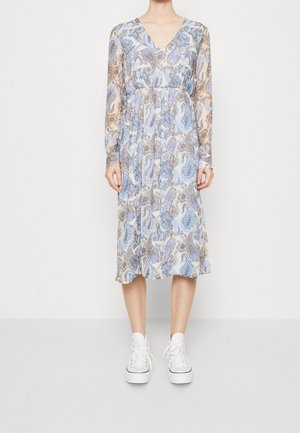 Pitkähihoinen, V-pääkoloa oleva mekko vaaleansinisena paisley-kuvioinnilla, laskeutuva kangas, polven pituinen, yhdistettynä valkoisiin tennareihin.