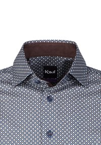 Camicia blu navy a maniche lunghe con un motivo geometrico bianco e azzurro chiaro. Bordo interno del colletto marrone e bottoni abbinati.
