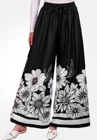 Pantalones de pierna ancha negros con estampado floral blanco, cinturilla elástica con cordón y una franja horizontal en contraste en la parte inferior.