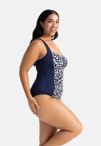 Üheosalinen ujumistrikoo, millel on tume sinine külg, rüüsitud detailid ja mustriga rinnaosa pastelse kujundusega. Reguleeritavad hati.