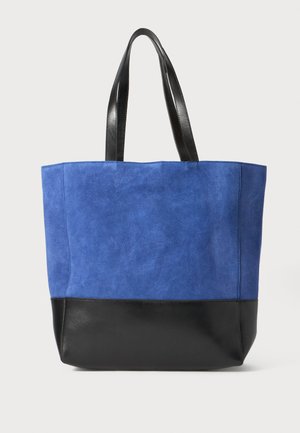 Borsa tote blu scamosciata con una base in pelle nera. Dotata di due manici robusti in pelle nera. Texture liscia e design semplice.
