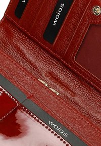 Interno di un portafoglio in pelle rossa con fessure per carte, un vano per le monete con chiusura metallica e una consistenza liscia. Nome del marchio "wojas" visibile.