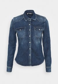 Chemise en jean bleu foncé à manches longues, fermeture à boutons sur le devant, deux poches poitrine à rabats avec boutons, et col pointu.