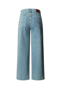 Jean denim bleu clair à jambes larges vu de dos avec deux poches arrière et un patch en cuir marron à la taille.