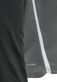 Gros plan sur un tissu sportif gris avec une bande blanche et le texte de la marque "BEECOOL" sur le bord inférieur d'un vêtement.