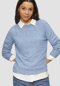 Lichtblauwe gebreide sweater met kabelpatroon, ronde hals en geribde manchetten, gelaagd over een witte overhemd met kraag. Casual pasvorm en gestructureerde stof.