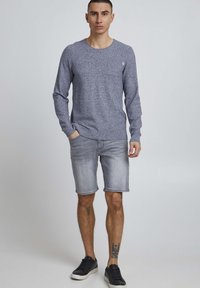 Long-sleeve, textured navy shirt with a round neckline, paired with gray denim shorts and black sneakers. Simple design, casual fit.