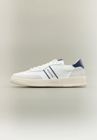 White sneaker with navy accents, featuring a textured suede heel, perforated details, and a rubber sole. "Valentino" logo on the side.