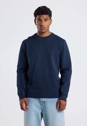 Sweatshirt bleu marine avec col rond et manches longues. Présente un ourlet et des poignets côtelés, fabriqué à partir d'un tissu lisse et doux.