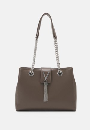 Sac à main en cuir marron avec des bandoulières en chaîne argentée et un détail pompon suspendu à une fermeture en forme de V sur le rabat avant.