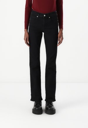 Black denim jeans with a straight leg fit, high waist, five-pocket design, and metallic button closure. Complemented by black platform shoes.