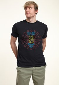 Camiseta de algodón negra con un gráfico colorido de un gato maneki-neko, rodeado de rayos rojos y el texto "Good Luck Ramen Bar Tokyo".
