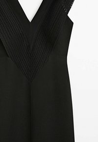 Robe sans manches noire avec un décolleté en V profond, orné d'une large bordure en tricot texturé s'étendant des épaules à la taille.