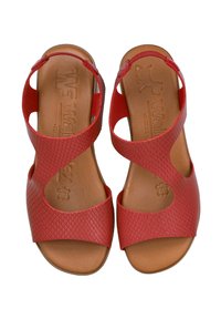 Sandalias rojas con parte superior de cuero sintético texturizado, diseño abierto y plantilla de espuma marrón. Cuenta con correas entrelazadas y detalles recortados.