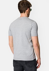 Szara bawełniana koszulka z krótким rękawem, dopasowany krój, minimalne detale przeszycia oraz logo marki blisko kołnierza z tyłu.