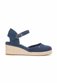 Espadrille compensée bleu marine avec bride à la cheville et boucle, semelle enveloppée de jute, avec petit logo rouge et blanc sur le bout.