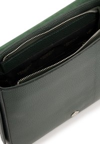 Grüne Ledertasche mit strukturiertem Finish, ausgestattet mit einer Reißverschlusstasche und einem Druckknopfverschluss. Innenausstattung aus schwarzem Stoff.