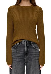 Maglione marrone caldo a maglia con una texture a coste, collo rotondo e maniche lunghe, abbinato a jeans grigi scuri a vita alta.