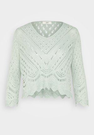 Lichtgroene cropped sweater met V-hals, lange mouwen en open breipatronen, waaronder een scalloped zoom en ingewikkelde geometrische ontwerpen.