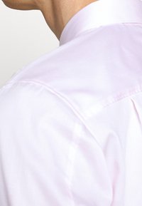 Koszula z kołnierzykiem w jasnoróżowym kolorze, wykonana z bawełny, charakteryzująca się gładką teksturą i klasycznym krojem, podkreślona starannie zszytymi szwami.