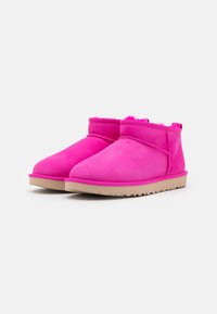 Stivali alla caviglia in suede rosa brillante con una morbida fodera, suola piatta beige e cuciture decorative lungo le cuciture.