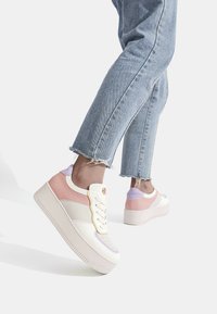 Sneakers platform con tomaia color crema, dettagli in rosa e lavanda, suola in gomma texturizzata e design classico con lacci.