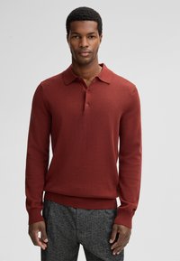 Bordeaux kleurige langharige polo trui met een kraag, voorzien van een knoopsluiting, geribde manchetten en een zoom voor een aansluitende look.