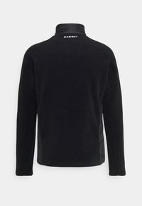 Chaqueta de forro polar negra con mangas largas, cuello alto y logo "Mammut" impreso en blanco en la parte superior de la espalda.