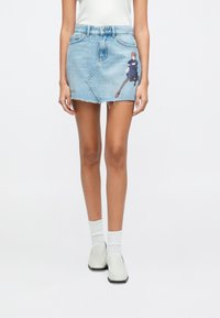Μινι φούστα από τζιν σε ανοιχτό μπλε με ξεφτισμένα τελειώματα, με γραφική εικονογράφηση στο μπροστινό μέρος. Κλασικός σχεδιασμός με πέντε τσέπες κ αι κλείσιμο με μεταλλικό κουμπί.