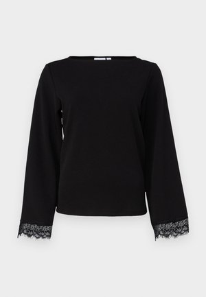 Melna ilga piedurkne blūze, izgatavota no mīkstas auduma, ar plašu kakla izgriezumu un mežģīņu apdari pie piedurknēm. Vienkāršs, taisns griezums.