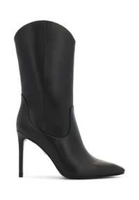 Bota alta de cuero negro con tacón y punta afilada. Presenta un diseño curvado, textura suave y un acento metálico en el tacón.