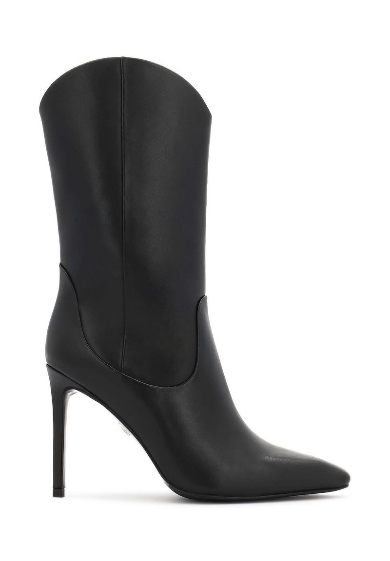 Bota alta de cuero negro con tacón y punta afilada. Presenta un diseño curvado, textura suave y un acento metálico en el tacón.