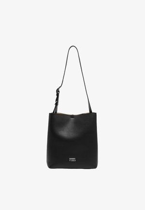 Sac fourre-tout en cuir noir avec une texture lisse, sangle ajustable et fermeture zippée en haut. Présente le nom de la marque en relief à l'avant.