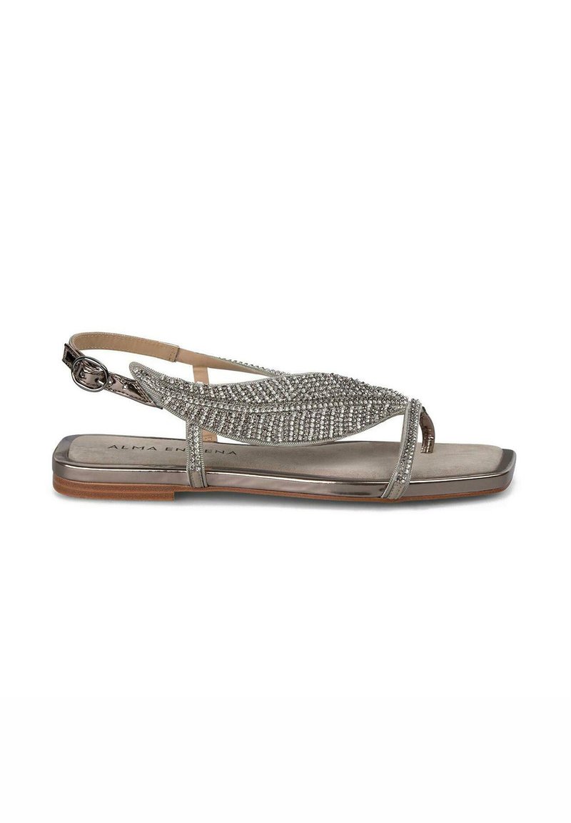 Sandal flat in argento metallico con un design impreziosito da strass. Caratterizzata da punta aperta e cinturino posteriore regolabile. Soletta liscia e opaca.