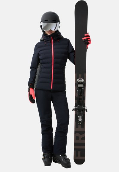 Skiausrüstung mit einer schwarzen Steppjacke mit roten Akzenten, schwarzen Schneehosen und Handschuhen. Trägt ein schwarzes Snowboard mit einer befestigten Bindung.