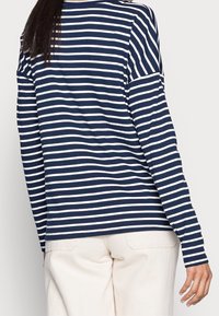Marineblau-weißer, gestreifter Langarmshirt im lässigen Schnitt. Der Stoff wirkt glatt und weich, mit einem Rundhalsausschnitt und lockeren Ärmeln.