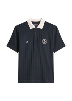 Σκούρο μπλε πόλο με κοντά μανίκια και κάθετες ρίγες, λευκό γιακά, δύο κουμπιά, λογότυπο "Marc O'Polo" στο στήθος και λευκό κεντητό κείμενο.