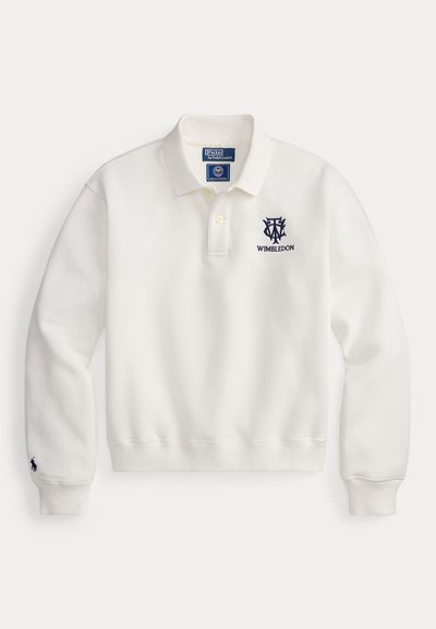 Polo blanc à manches longues avec col, deux boutons, logo Wimbledon sur la poitrine et petit logo Ralph Lauren sur le poignet gauche.