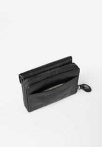 Portafoglio in pelle nera con chiusura a zip, dotato di una tasca frontale. Texture liscia e design semplice con attacco a bottone a scatto.