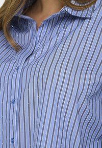 Blauw gestreept overhemd met knopen, voorzien van dunne verticale witte strepen en kleine zilveren stippen. Lichtgewicht stof met een gladde textuur.