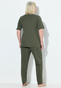 Camiseta verde oliva de manga corta combinada con pantalones verde oliva con lunares. Tejido suave con un corte holgado, con un escote redondo y largo hasta los tobillos.