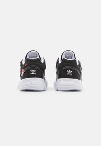 Zapatillas deportivas negras con parte superior texturizada, suelas blancas y detalles bordados. Cuenta con un collar y lengua acolchados para mayor comodidad.