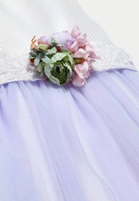 Bodice bianco testurizzato con rifiniture in pizzo, accento floreale attaccato in rosa e verde, gonna in tulle lavanda a strati con tessuto morbido e trasparente.