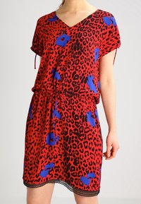 Vestido rojo con un estampado de leopardo que presenta acentos florales azules. Mangas cortas, escote en V, cintura ceñida y dobladillo con encaje.