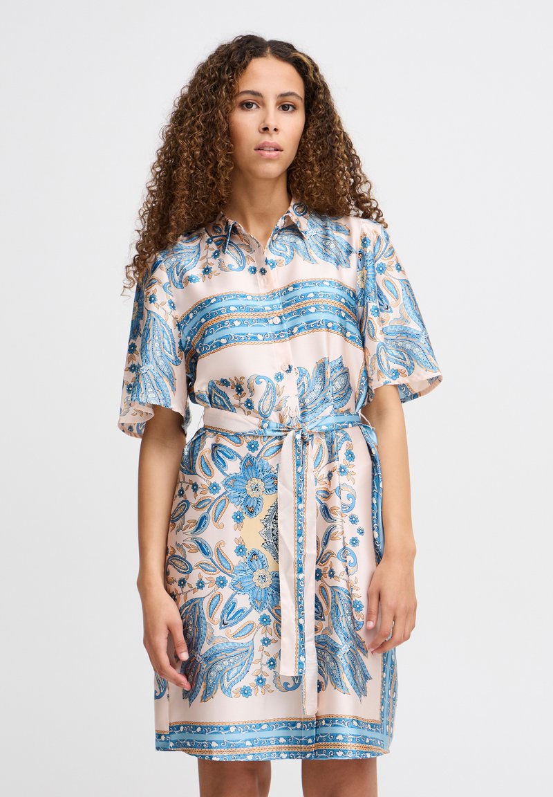 Rochie cu mânecă scurtă din mătase, cu un model paisley albastru pe un fundal roz deschis, având talie strânsă și curea asortată.