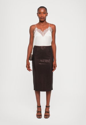 Camisola bianca con bordo in pizzo abbinata a una gonna a matita fitted di paillettes scure. La modella indossa dei tacchi neri con tracolla e tiene una piccola borsa.
