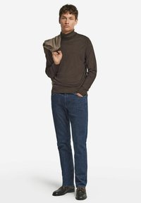 Brauner Rollkragenpullover, Jeans und schwarze Schuhe. Der Pullover hat eine glatte Textur; die Jeans sind eng geschnitten und haben eine klassische blaue Farbe.